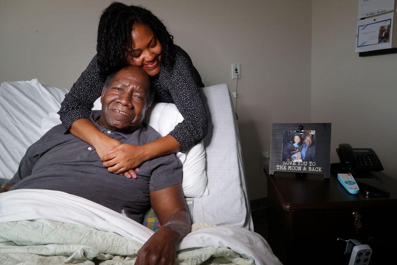 woman hugging dad who in a hospital chair