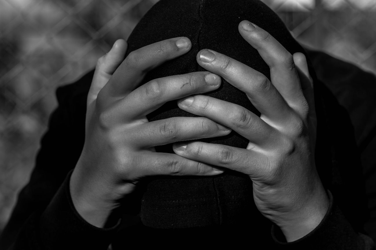 boy covering face black and white photo