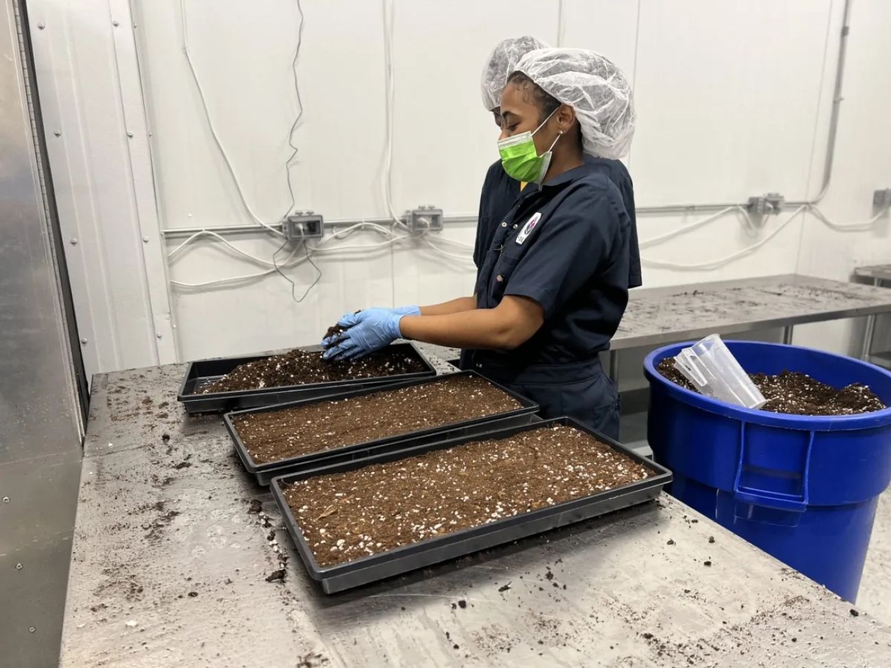 a worker putting dirt into a black planter