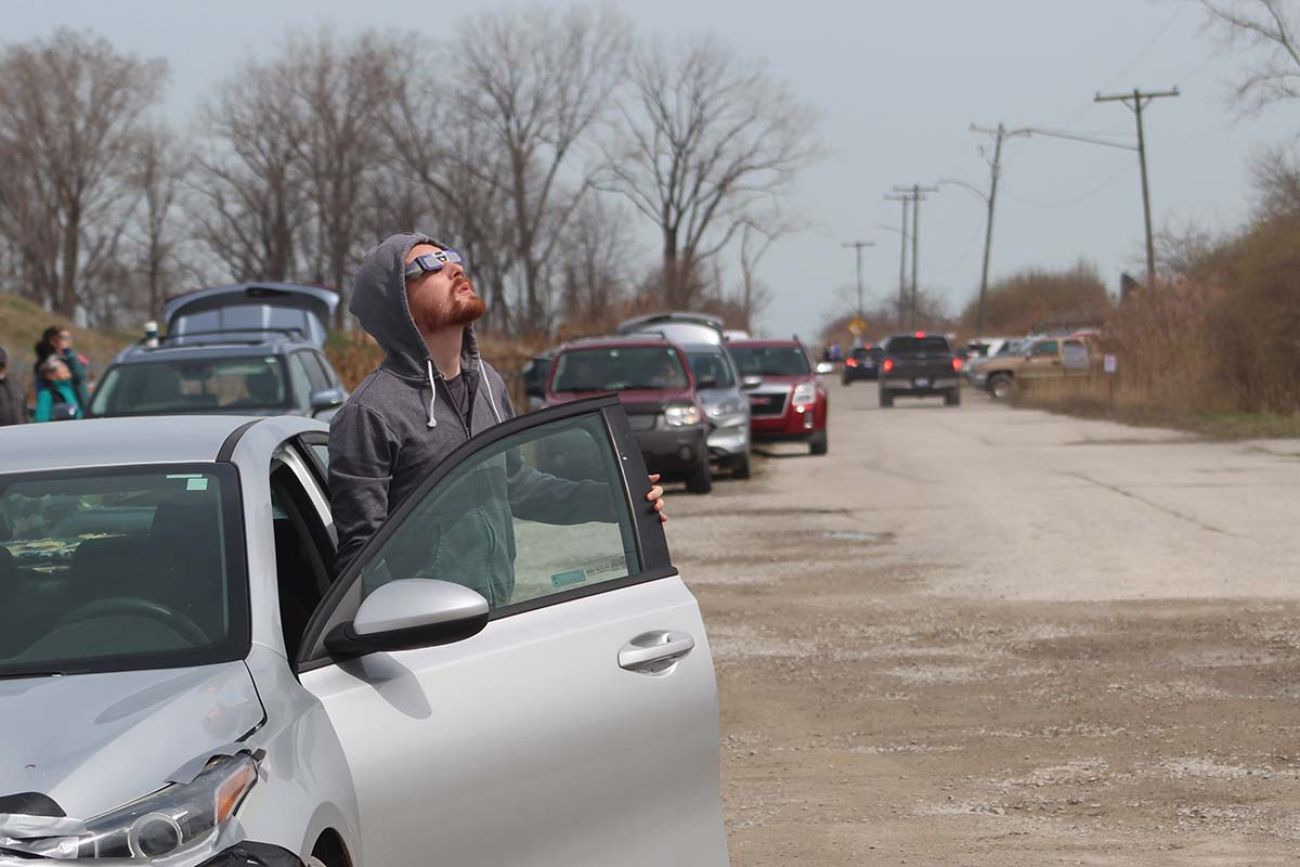 people pulled on the side of the road looking at the sky