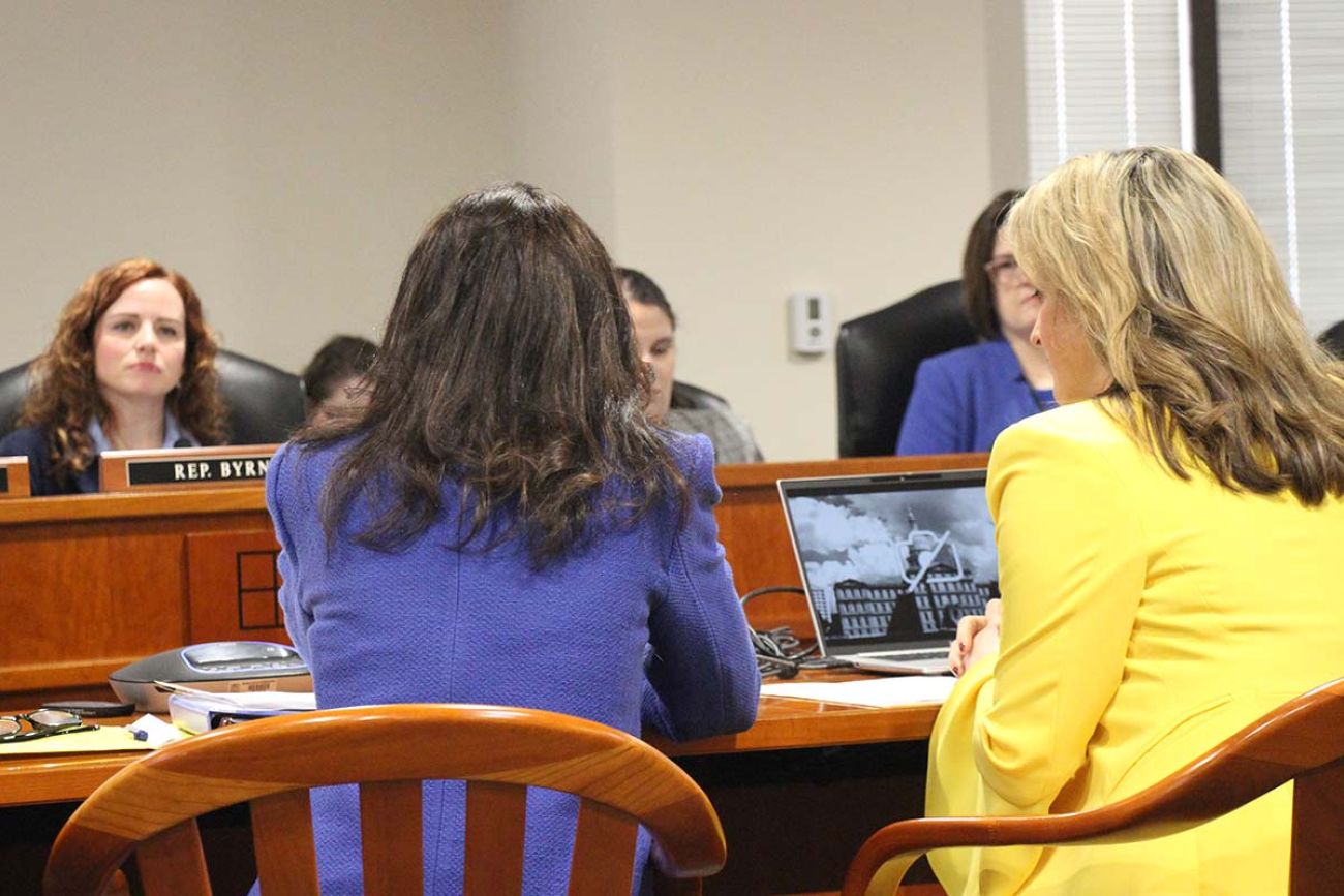 people sitting in a room, Attorney General Dana Nessel and Secretary of State Jocelyn Benson back is turned to the camera