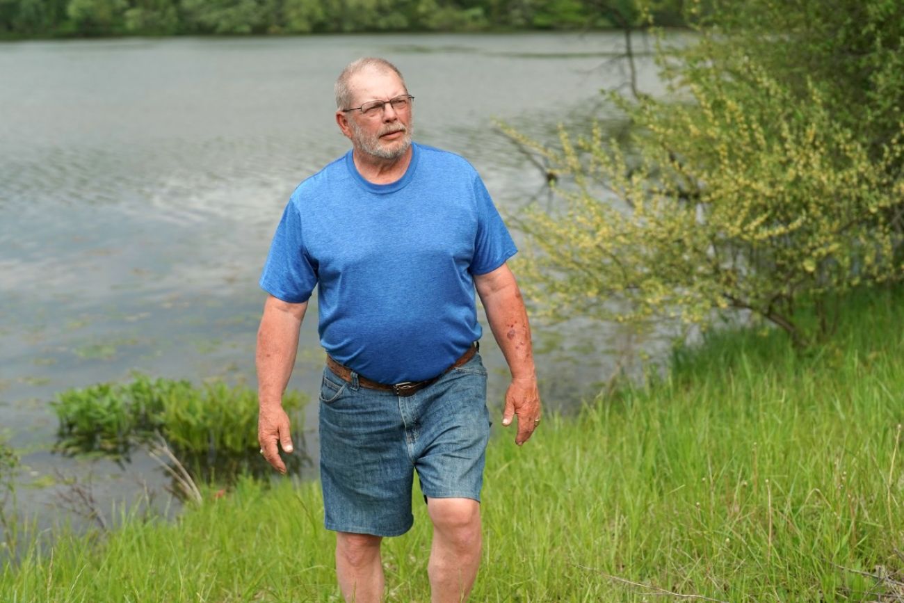 Man wearing a blue shirt, walking outside. 