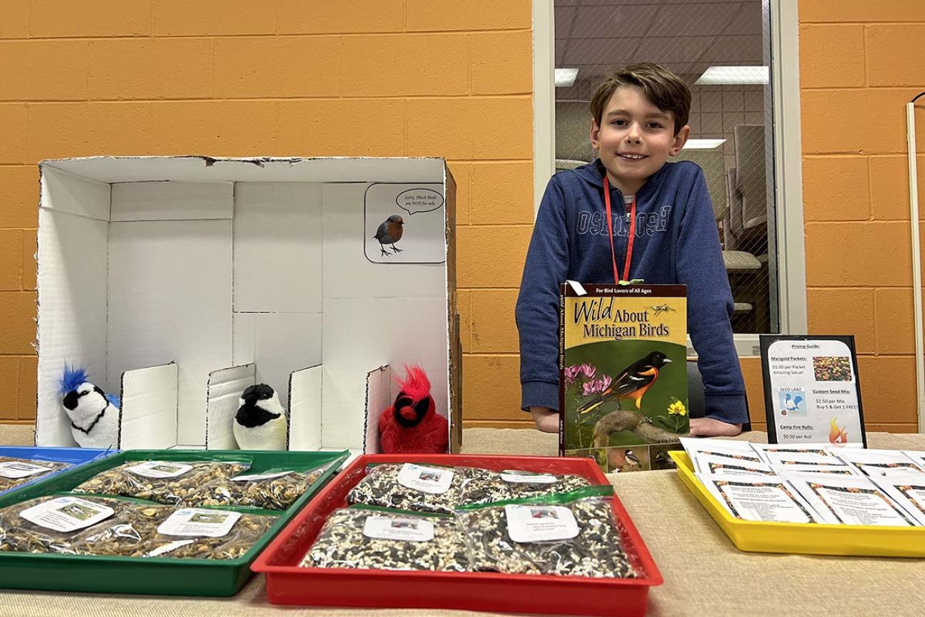 a young boy standing behind a table