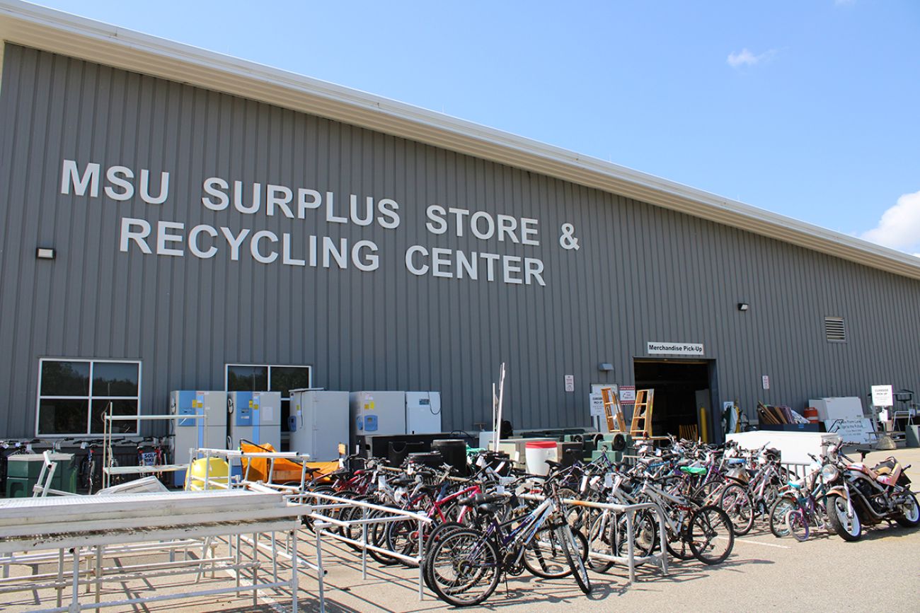 Outside the Michigan State University Surplus Store and Recycling Center, a grey building 