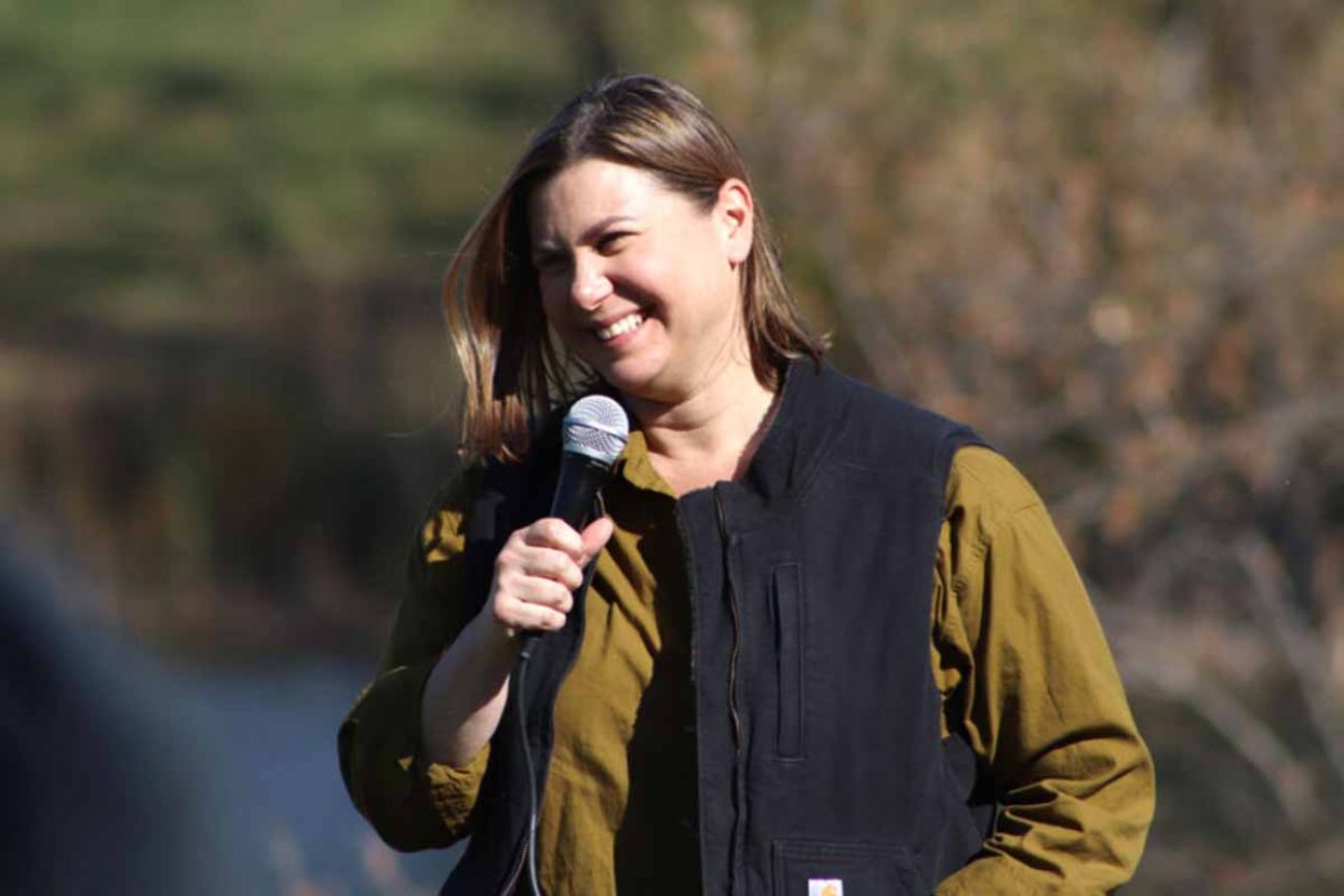 Elissa Slotkin, wearing a green long sleeve shirt and black vest, speaking into a microphone