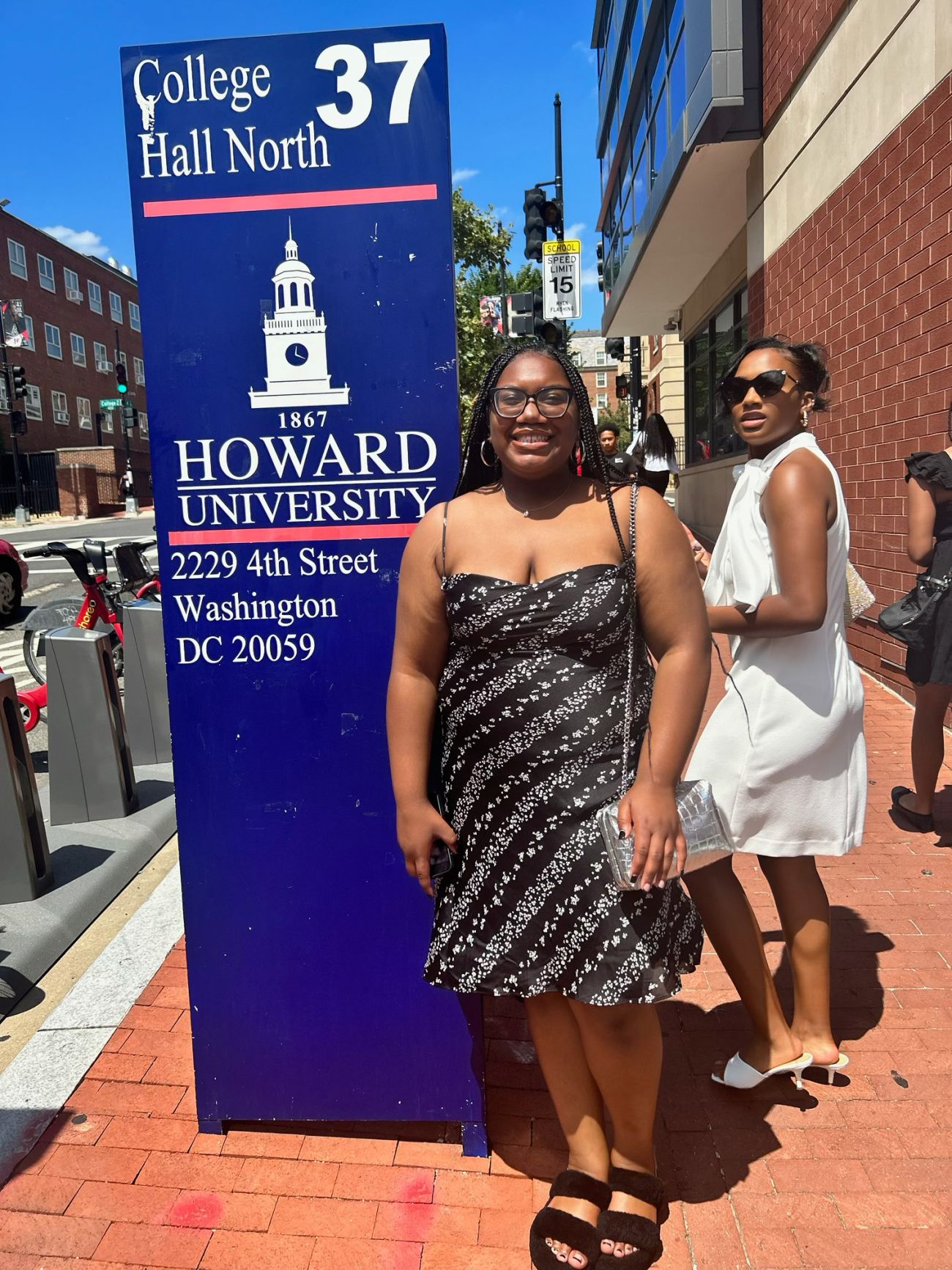 Young woman posing in front of a blue sign for Howard University in Washington, D.C.