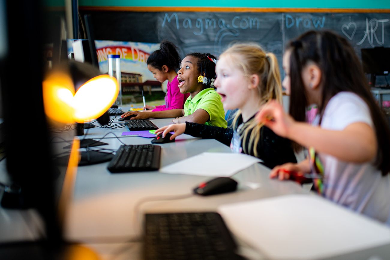 Four kids in front of a computer in a classroom