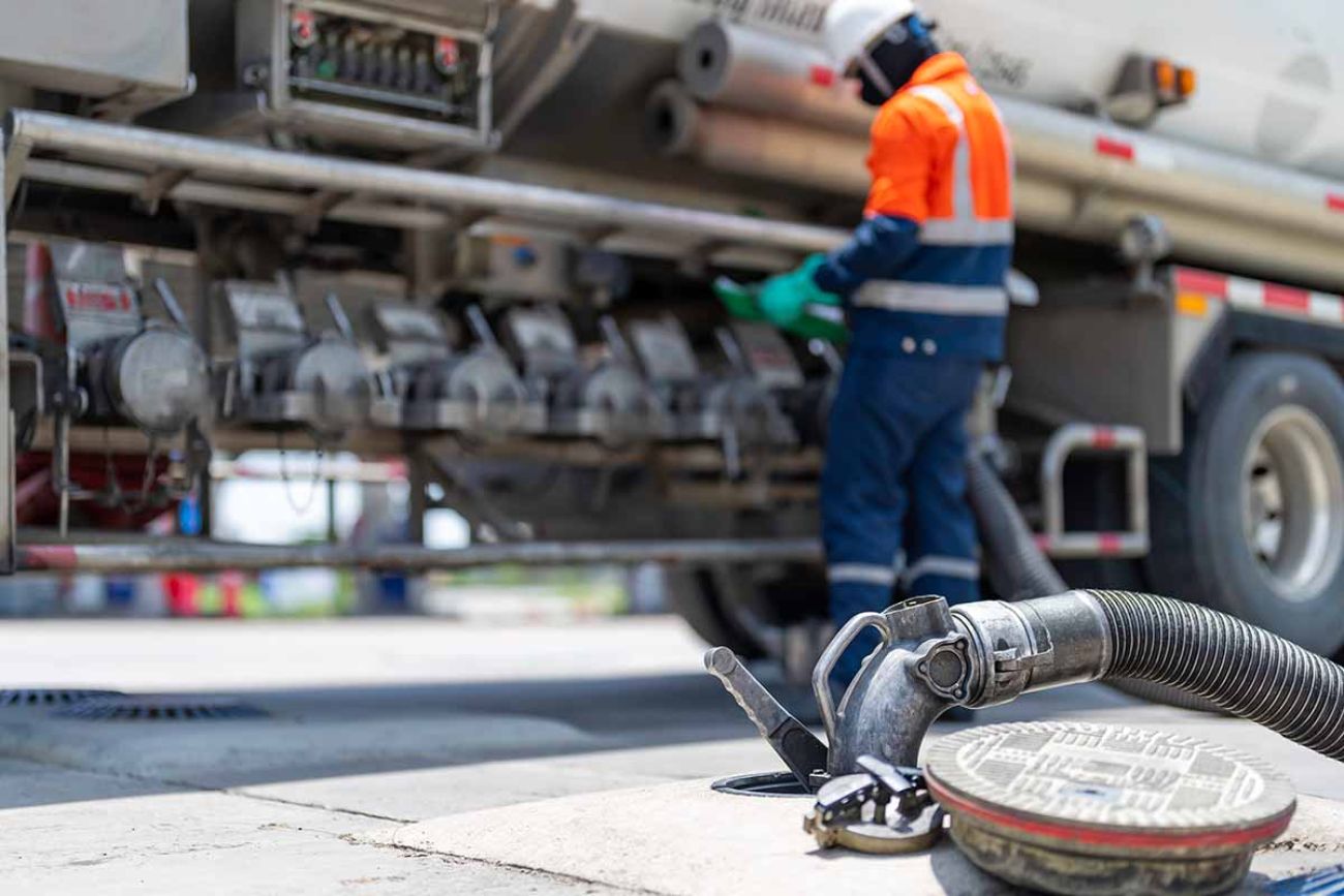 A tanker truck driver delivers gasoline to a gas station