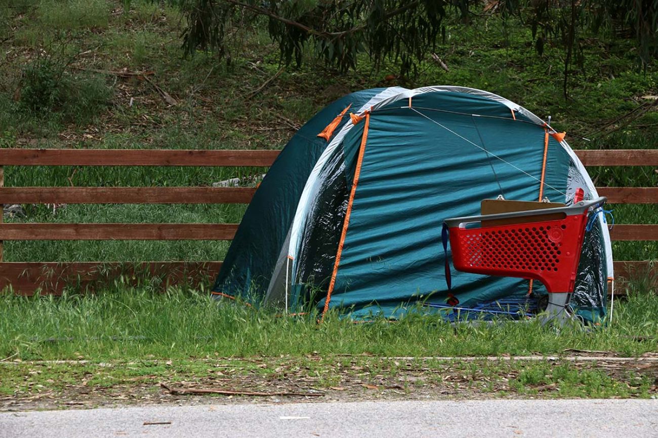 A bright red cart stands next to a blue tent used by a homeless person, A pending decision by the U.S. Supreme Court will decide whether governments can ban homeless camps in Michigan and other states. 