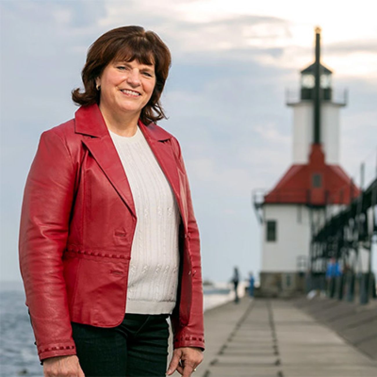 Sherry O’Donnell, wearing a red jacket, stands in front of a lighthouse