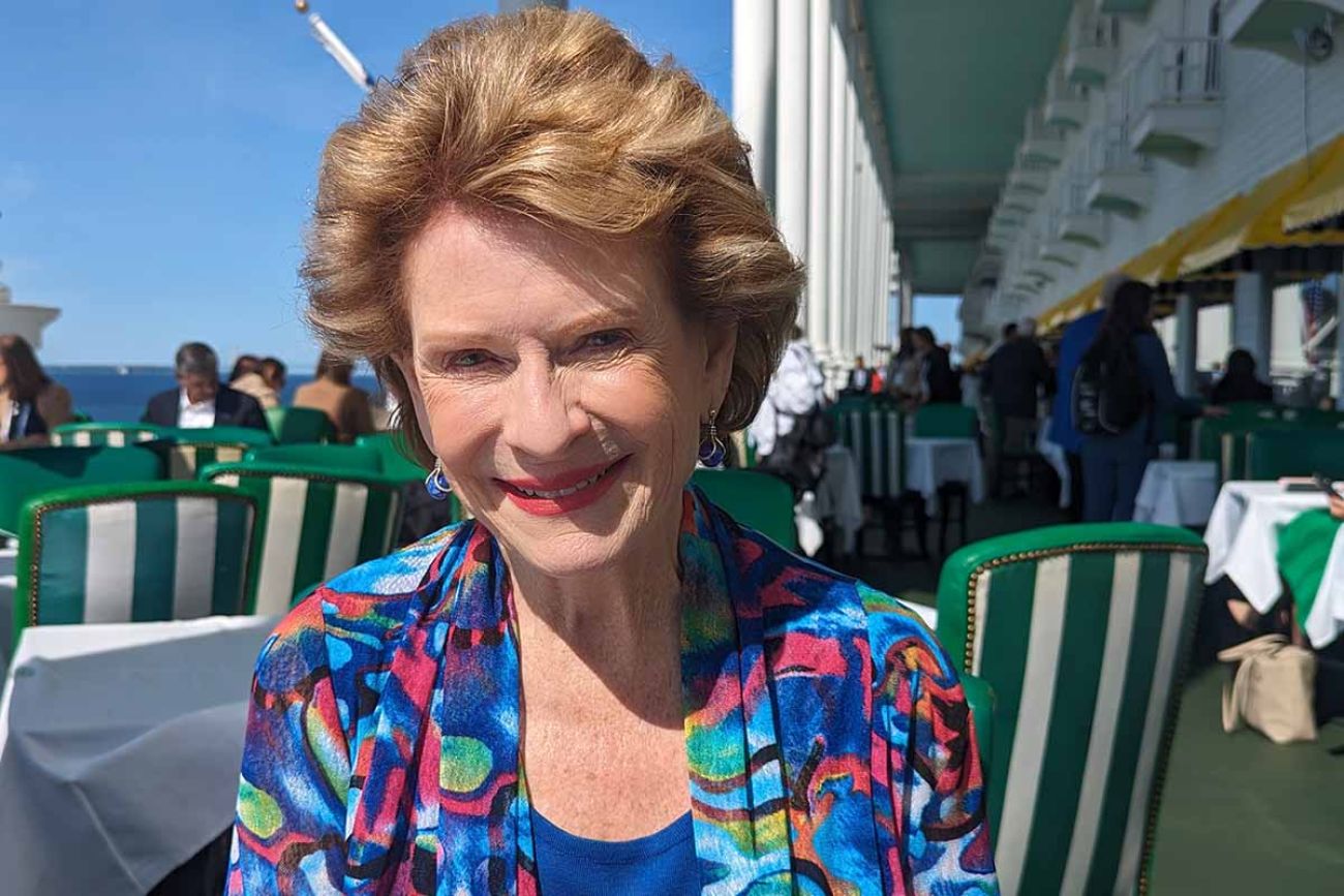 Debbie Stabenow, wearing a colorful shirt, sitting at the porch of the Grand Hotel