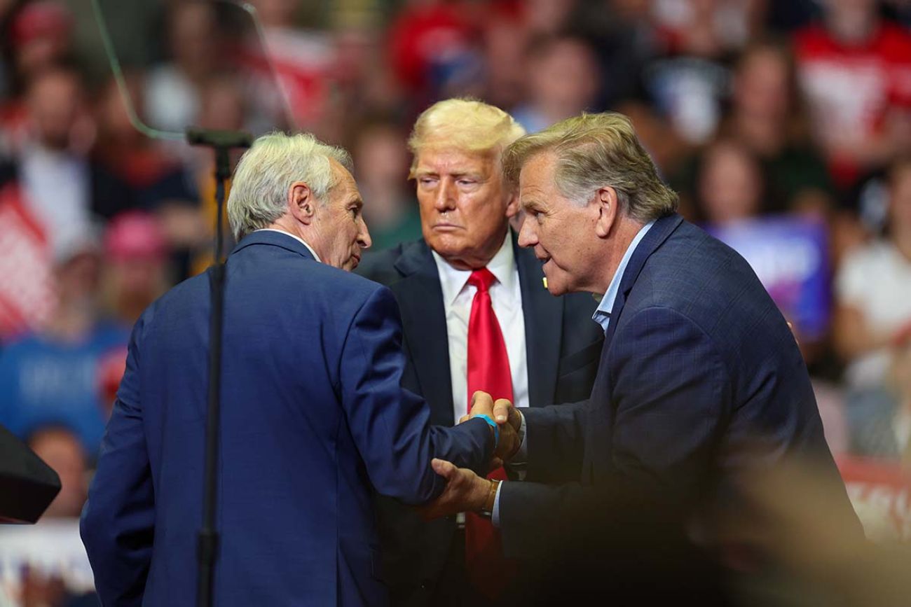 Business executive and former U.S. Senate candidate Sandy Pensler shakes hands with Republican front-runner Mike Rogers on stage. Supporters behind him