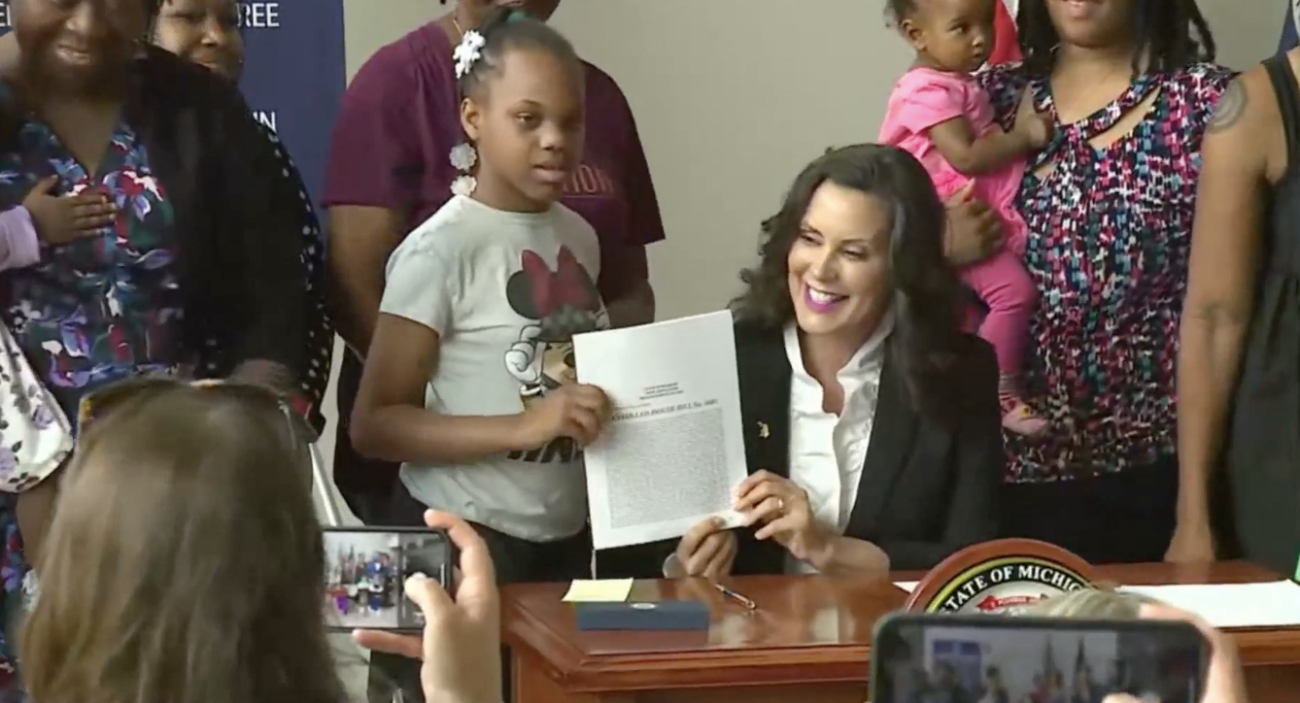 Michigan Gov. Gretchen Whitmer holding up a paper next to a child