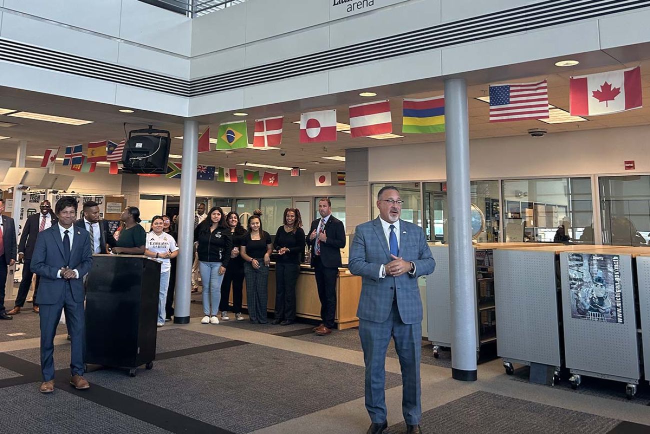 U.S. Secretary of Education Miguel Cardona standing and talking at Cass Technical High School in Detroit. People are standing behind him, listening 