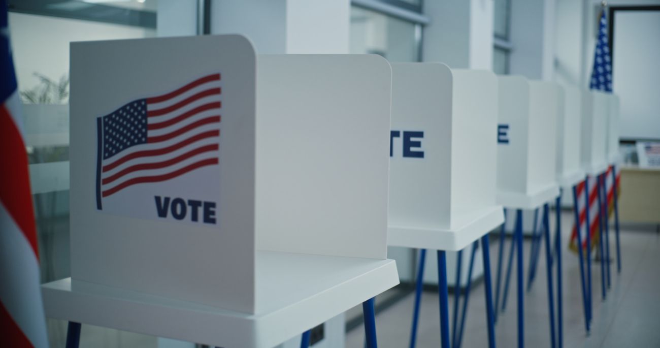 Voting booths with American flag logo in bright polling station office. 