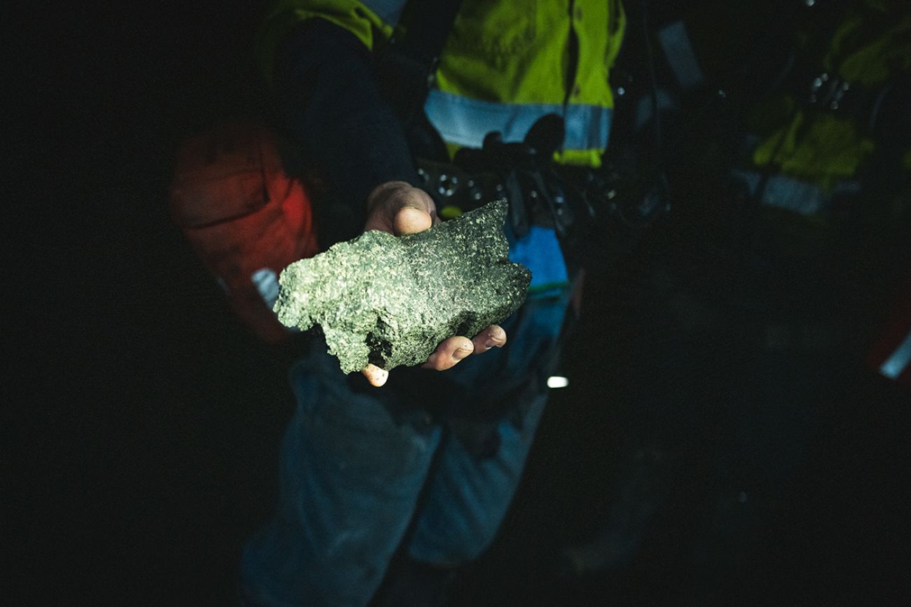 A man holding a shimmering copper and nickel sulfide