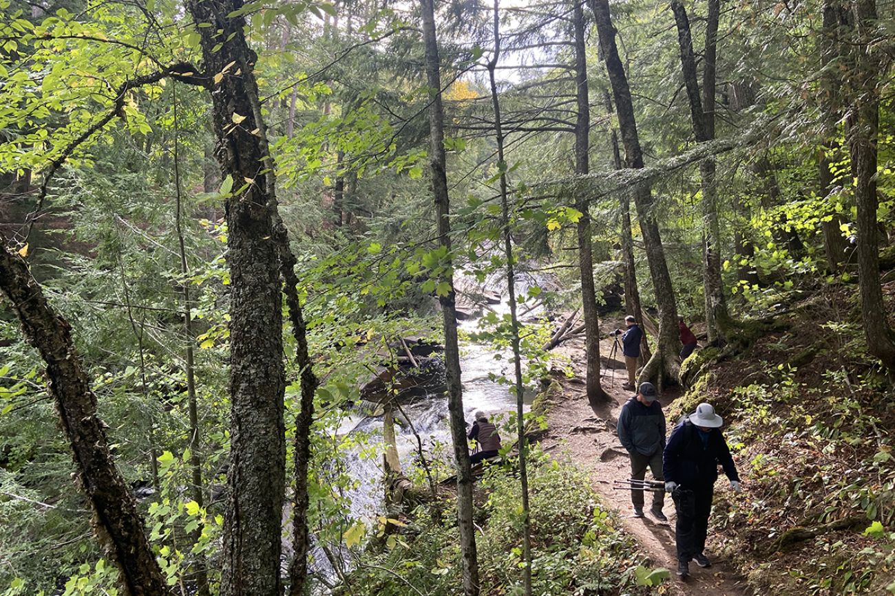 People hiking next the Presque Isle River. You can see trees and the river