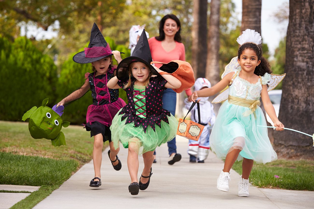 Parent Taking Children Trick Or Treating At Halloween