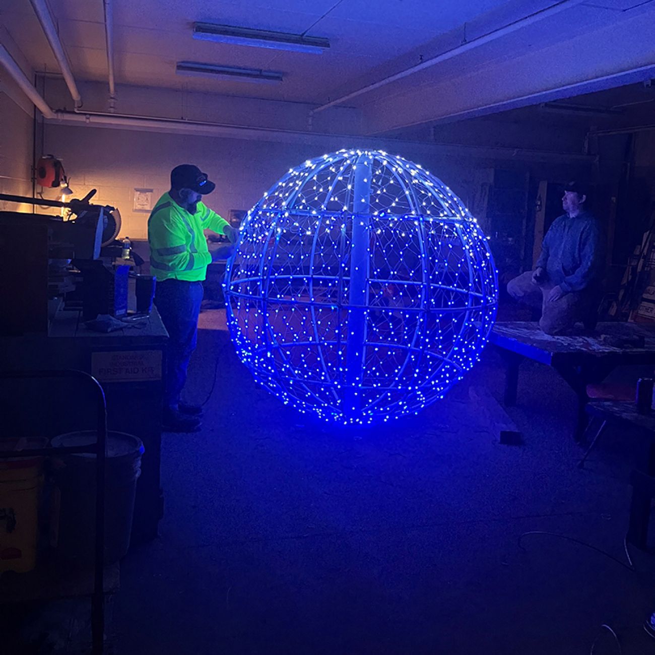 People working a sphere made of blue lights