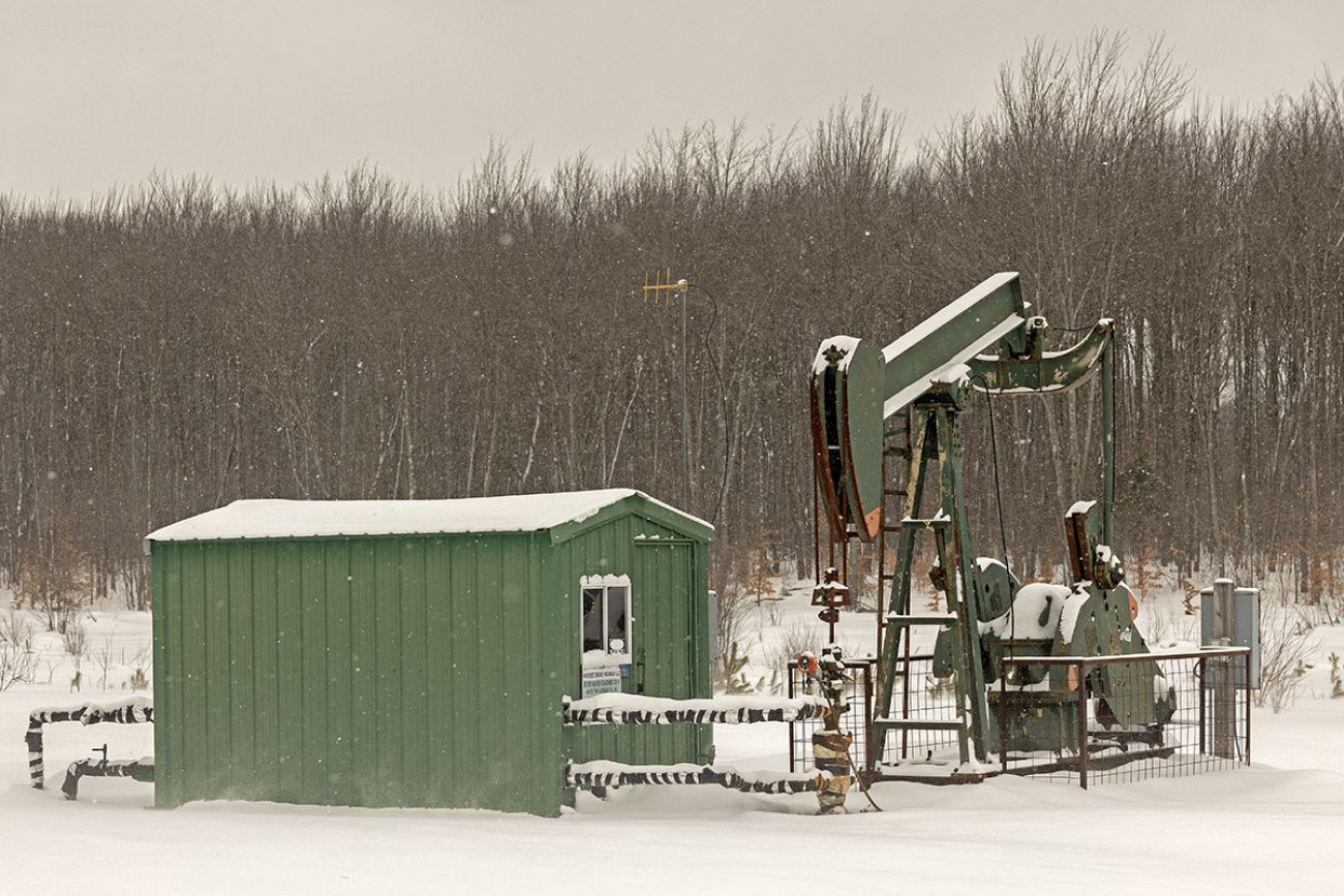 A green shed next to an oil well. It's snowy outside