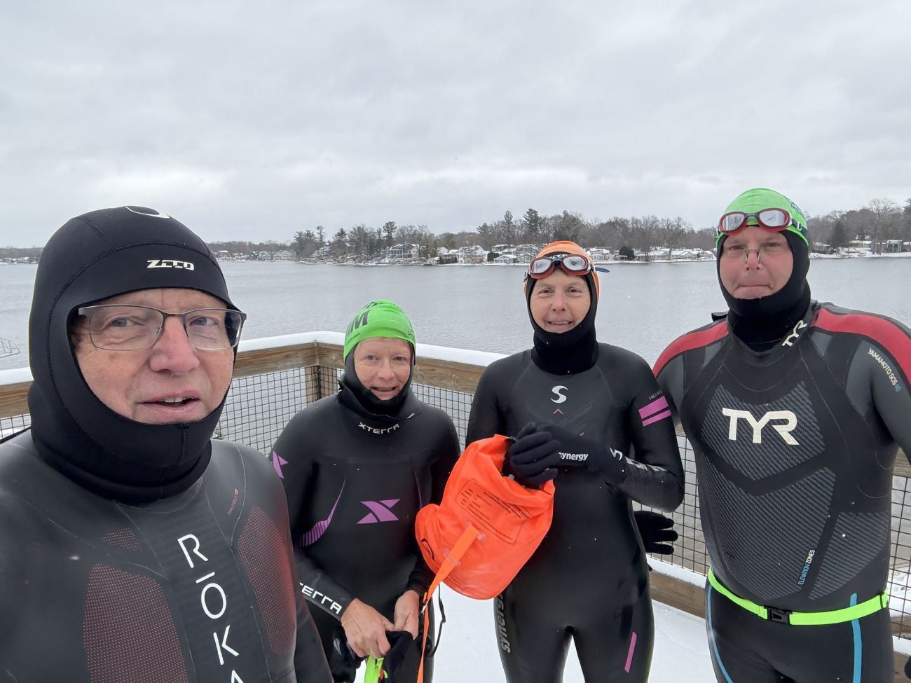 A group of people pose for a picture. They are wearing wet suits. 