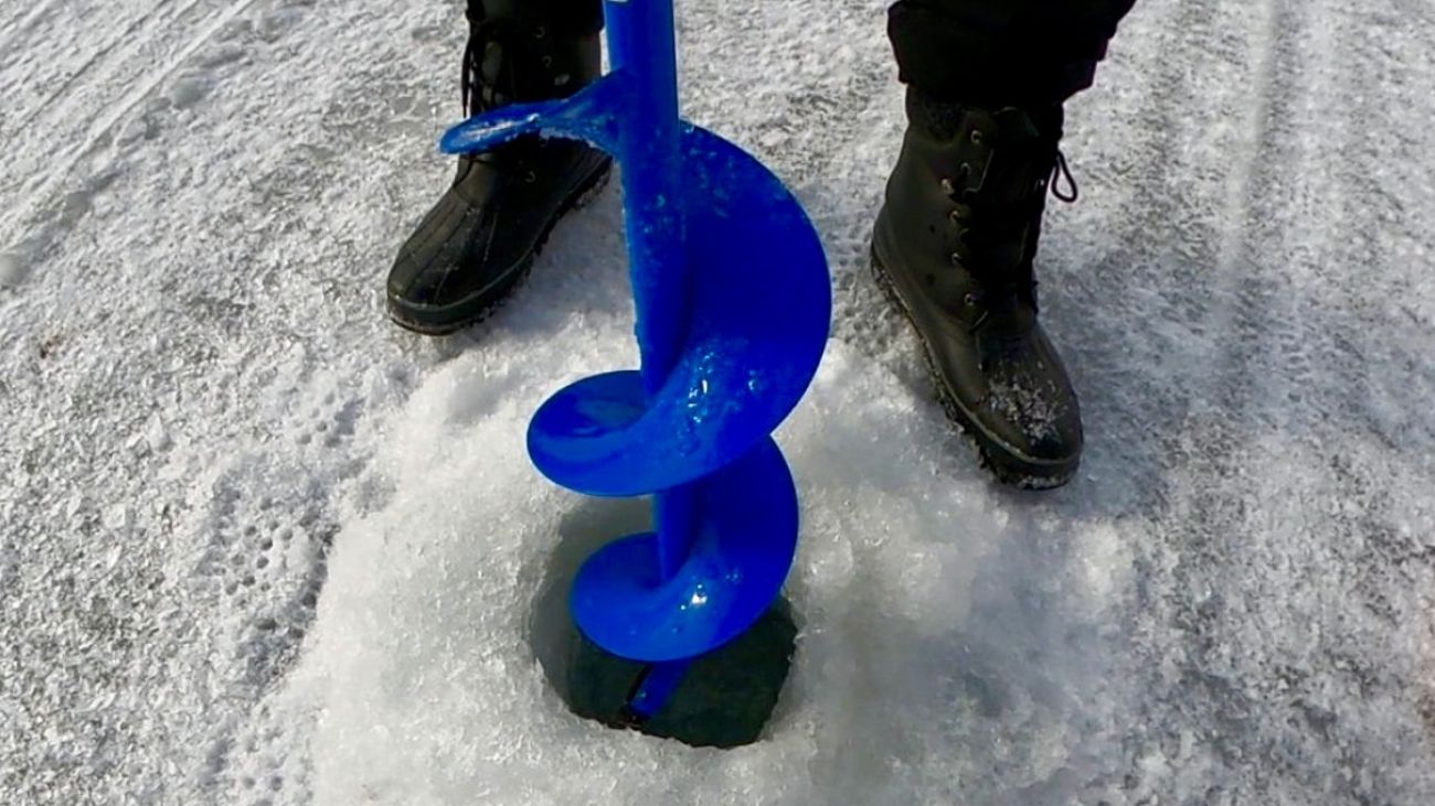 Someone cutting a hole in ice with an auger. 