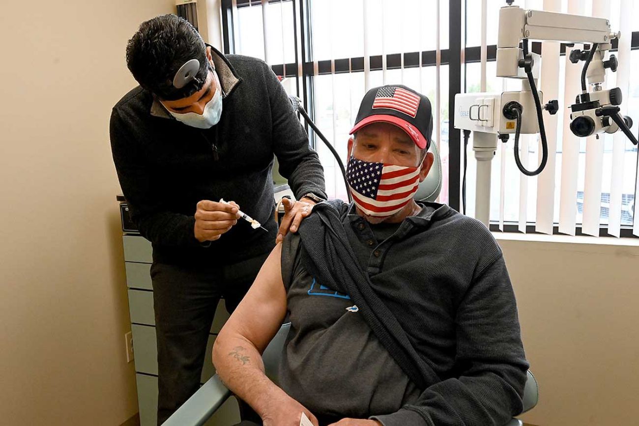 Dr. Bobby Mukkamala gives the COVID-19 vaccine to a man. 