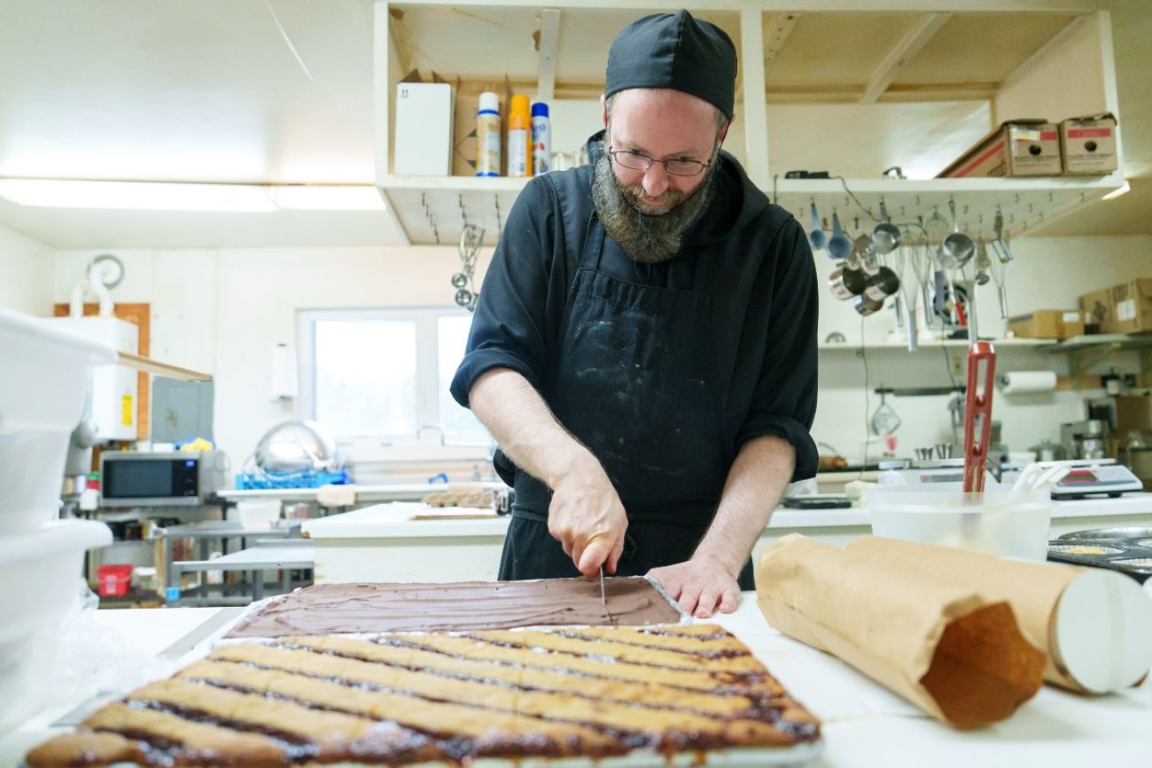 A man cuts a pastry on a pan