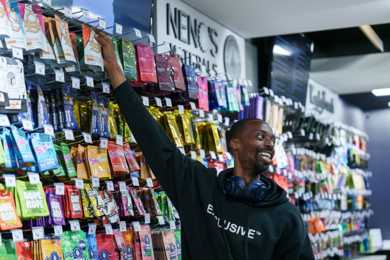 A man reaches up to grab a product from a wall full of marijuana products
