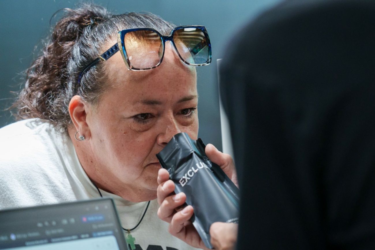 A man holds up a bag of cannabis product and a woman sniffs the bag