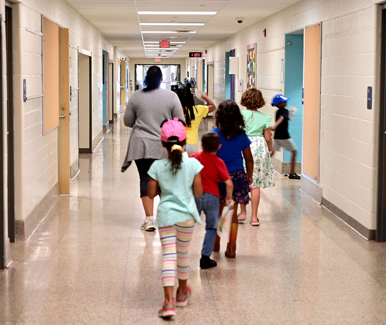 A teacher walks with students in the hallway.