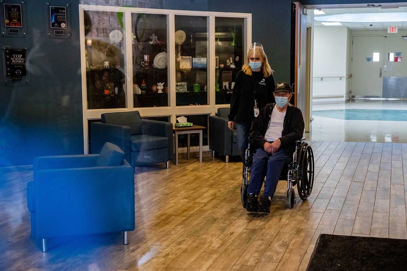 Diana Masters, activity director, walks Clarence "Bo" Whitmeyer to his visit with his daughters in medial care facility