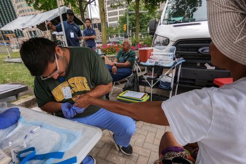 person collecting blood from another person outside