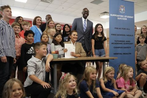 Gov. Gretchen Whitmer signing a bill surround by kids