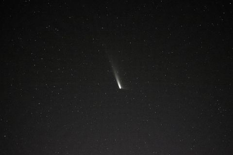 A comet, which looks like a white burst of light, at the dark sky