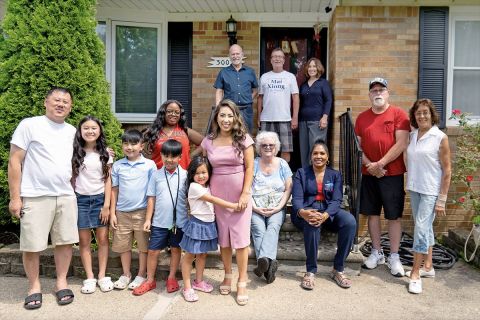 Rep. Mai Xiong poses with her family in front of a house