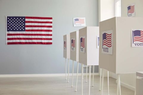 White empty voting booths at polling station with American flag