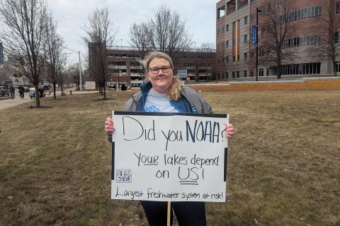 Nicole Rice holds a homemade sign supporting NOAA. 