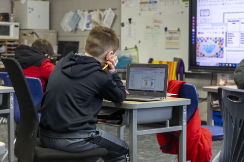 A student looking at this laptop in a classroom. 