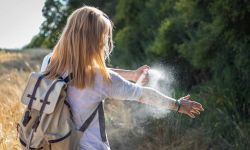 Woman applying mosquito repellent on hand during hike in nature