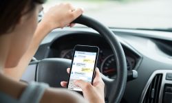 Close-up Of Woman Sitting Inside Car Typing Text Message On Mobile Phone