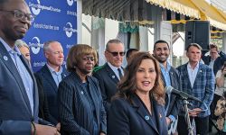 Gov. Gretchen Whitmer at the microphone surrounded by people