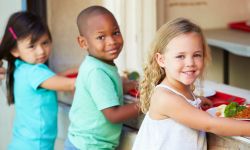 Children stand in lunch line.