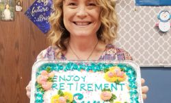 Susy Talentino holding up cake that says "happy retirement susy"