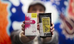 man holds up two naloxone kits