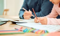 dad and daughter doing school work on table