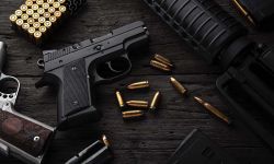 Gun with ammunition on dark wooden background