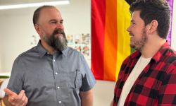 Two people talking to each other. One is wearing a grey shirt and the other is wearing a red fannel