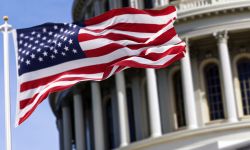  The flag of the united states of america flying in front of the capitol building blurred in the background. 