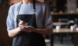 Woman cafe worker with notebook in hands waiting for an order